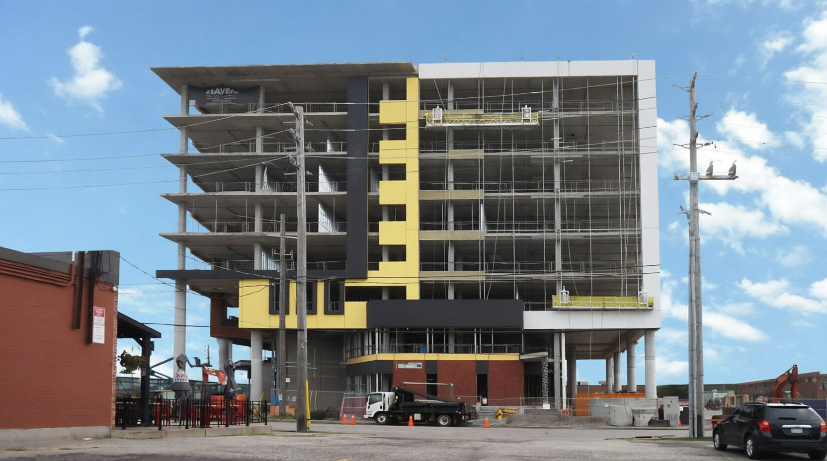 Mid-rise residential building under construction with yellow panel accents